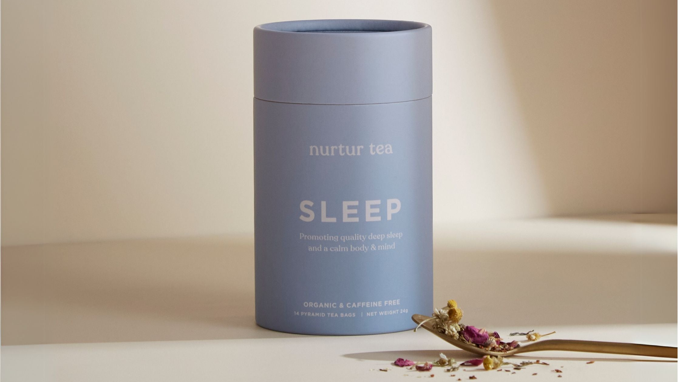 Nurtur Tea’s sleep tea packaging in a plain background with a spoon of some loose leaf teas